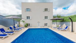 a pool with chairs and umbrellas next to a house at Star Hill - Makarska by Villas Guide in Slivno