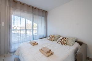 une chambre avec un grand lit blanc avec des serviettes dessus dans l'établissement Grand Studio front de mer - Climatiser avec place de parking, à La Celle-sous-Gouzon