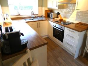 una cucina con mobili bianchi e un forno a piano cottura di The Saddlery Holiday Cottage - Near Wolds And Coast a North Thoresby