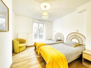 2 bedden in een slaapkamer met een gele stoel bij Au jardin de la Basilique in Boulogne-sur-Mer