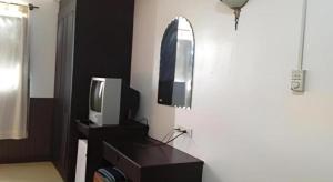 ein Zimmer mit einem Fernseher und einem Spiegel an der Wand in der Unterkunft Senesouk Hotel in Vientiane