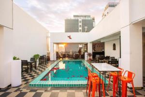een zwembad met oranje stoelen en tafels in een gebouw bij Wind Holiday Hotel in Phnom Penh