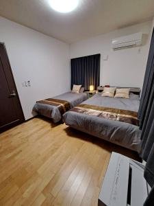 a bedroom with two beds and a desk with a laptop at CONDOMINIUM Yomitan 蔵 in Yomitan