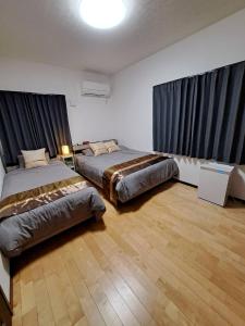 two beds in a large room with black curtains at CONDOMINIUM Yomitan 蔵 in Yomitan