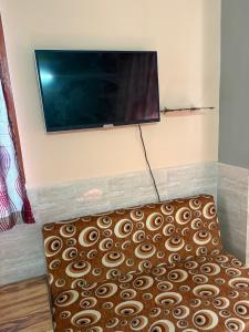 a flat screen tv hanging on a wall with a couch at Hotel Mohan in Agra