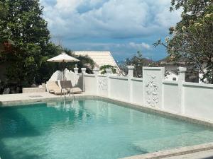 a swimming pool with a white fence and an umbrella at Bounty Resort in Haad Son