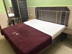 a bed in a room with a maroon blanket at Hotel Mohan in Agra