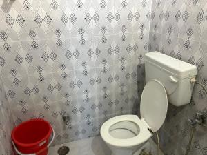 a bathroom with a white toilet and a red bucket at Hotel Mohan in Agra