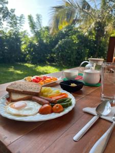 a plate of breakfast food on a wooden table at Space Hiri - Hiriketiya in Nilwella