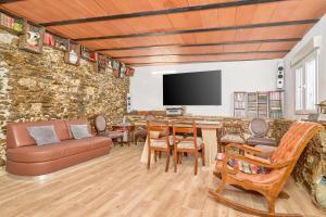 ein Wohnzimmer mit einer Steinmauer und einem TV in der Unterkunft Cortijo Palomo in Benamocarra