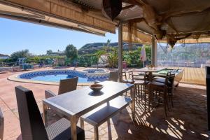 eine Terrasse mit Tischen und Stühlen sowie einem Pool in der Unterkunft Cortijo Palomo in Benamocarra