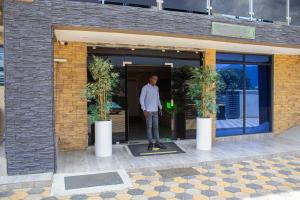 Ein Mann steht in der Tür eines Gebäudes in der Unterkunft LENNON QUALITY Hotel in Umtali