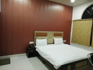 a bedroom with a bed and a red wall at Hotel Ram Bhawan in Lucknow