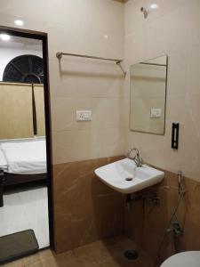 a bathroom with a sink and a mirror and a bed at Hotel Ram Bhawan in Lucknow