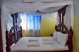 ein Schlafzimmer mit einem Himmelbett und Handtüchern darauf in der Unterkunft Rhino Apartments in Watamu