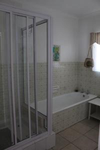 une salle de bain avec baignoire et douche en verre dans l'établissement Die Dik Vis, à Velddrif 24 autres photos