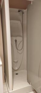 La salle de bains blanche est pourvue d'une douche avec un tuyau. dans l'établissement Location d'un chalet de vacances, à Pont-de-Poitte