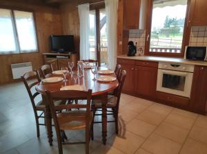 een eetkamer met een tafel met stoelen en een keuken bij Location d'un chalet de vacances in Pont-de-Poitte