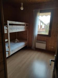 een slaapkamer met twee stapelbedden en een raam bij Location d'un chalet de vacances in Pont-de-Poitte