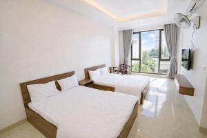 ein Hotelzimmer mit zwei Betten und einem Fenster in der Unterkunft Hiếu Thảo Hotel & Restaurant Sầm Sơn in Sầm Sơn