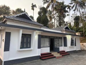 a small white building with palm trees in the background at The Coffee Cube in Kaniyāmbetta