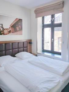 a white bed with a window in a bedroom at Dancenter Hotel Jomfru Ane in Aalborg