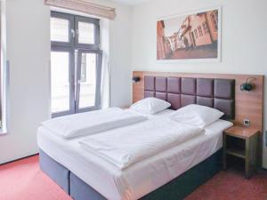 sypialnia z dużym łóżkiem z białymi prześcieradłami w obiekcie Dancenter Hotel Jomfru Ane w Aalborgu