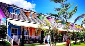 une femme debout devant une maison colorée dans l'établissement Chiangkhan Gallery Resort, à Chiang Khan