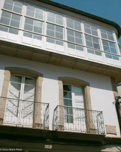 a white building with windows and balconies at A galería do san Ramón in Villalba