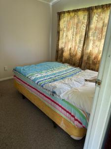 een klein bed in een kamer met een gordijn bij Bayfair Backpack House in Tauranga +2 foto's
