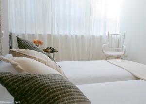 a bedroom with a bed with a chair and a window at A galería do san Ramón in Villalba
