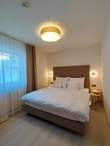 een slaapkamer met een groot bed met witte lakens bij das Alpenblick & Outdoor Lodge Nauders in Nauders