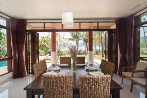a dining room with a table and chairs and windows at Amatapura Beachfront Villa 1, SHA Certified in Ao Nam Mao