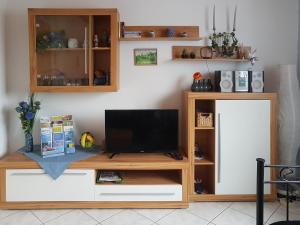 ein hölzernes Unterhaltungszentrum mit einem Fernseher darüber in der Unterkunft Ferienwohnung Wilpert in Schwanfeld