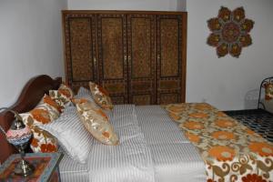 een bed met kussens erop in een slaapkamer bij Chambres Émeraude et Rubis - Riad Lotus Bleu in Fès