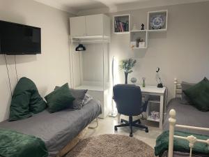 a living room with a couch and a desk with a chair at Costa del Pinner in Northwood