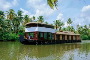 a house boat on a river with a building on it at Shivaganga Houseboat- VACCINATED STAFF in Kumarakom