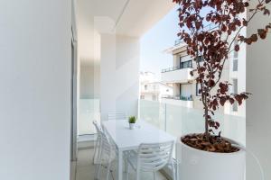 een witte tafel en stoelen op een balkon met een boom bij Homiday - Sublimare in Giulianova