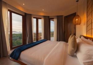 une chambre avec un grand lit avec une grande fenêtre dans l'établissement Atalaya Resort El Nido, à El Nido