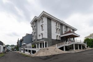 een groot wit gebouw aan de kant van een straat bij RedDoorz Plus near Universitas Maranatha Bandung 2 in Bandung