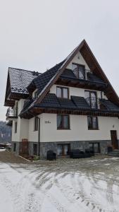 a large house with a roof in the snow at Pokoje gościnne u Sołtysów in Jurgów