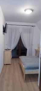a bedroom with a bed with curtains and a wooden floor at Pokoje gościnne u Sołtysów in Jurgów +3 photos