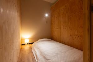 a small bedroom with a bed and a lamp at くにまるイン in Kyotango