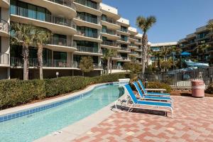 a swimming pool with two blue chairs in front of a building at Phoenix on the Bay Unit 1110 in Orange Beach