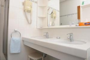 a white bathroom with two sinks and a mirror at Landgasthof Hotel Muhr in Gallbrunn