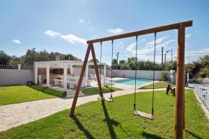 a swing set in a yard with a pool at Villa Anastasis in Halikounas