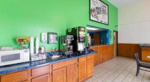 a kitchen with green walls and a counter with a microwave at Super 8 By Wyndham Wayne in Wayne