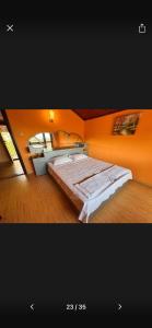 een slaapkamer met een groot bed met een oranje muur bij Вила Хоризонт-Албена in Balchik