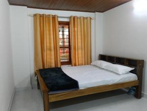 a bedroom with a bed and a window at Anurastays in Mudigere