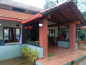 a house with a brick roof and a patio at Anurastays in Mudigere